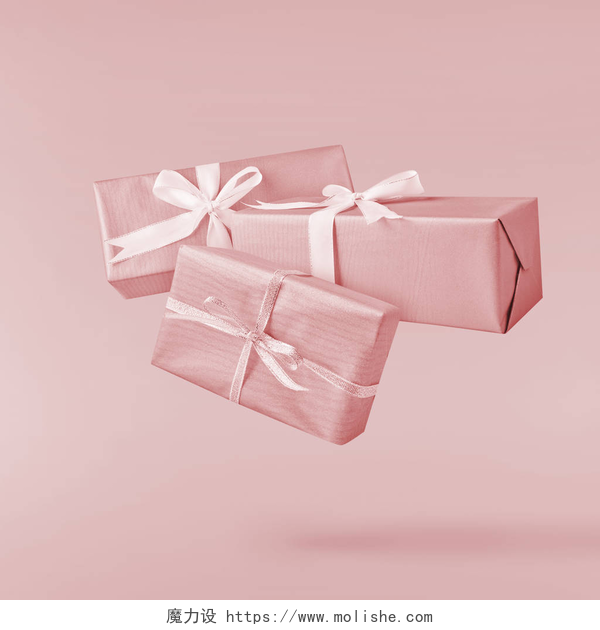 粉色背景下的三个粉色礼物盒圣诞节的概念。创意圣诞构想, 通过下降在空气礼品盒超过粉红色的背景。最小的概念